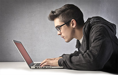 młody człowiek siedzi przed laptopem