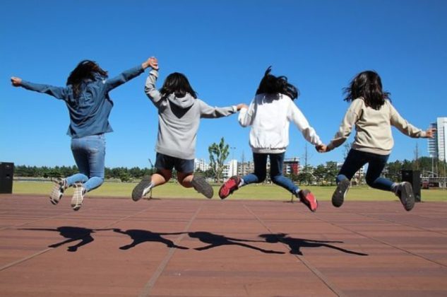 4 dziewczyny skaczą na boisku trzymając się za ręce